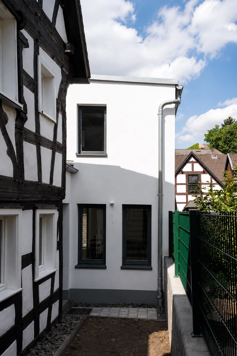 Neubau mit weißer Fassade neben einem Fachwerkhaus unter Denkmalschutz in Königswinter