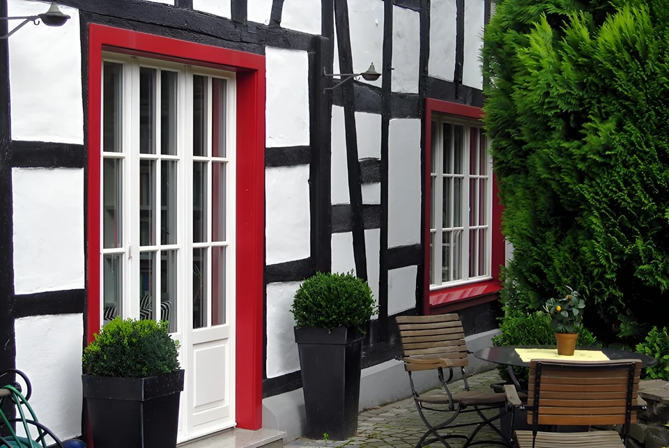 Fachwerkhaus mit roten Fensterrahmen und Sitzplatz im Hof in Bad Honnef
