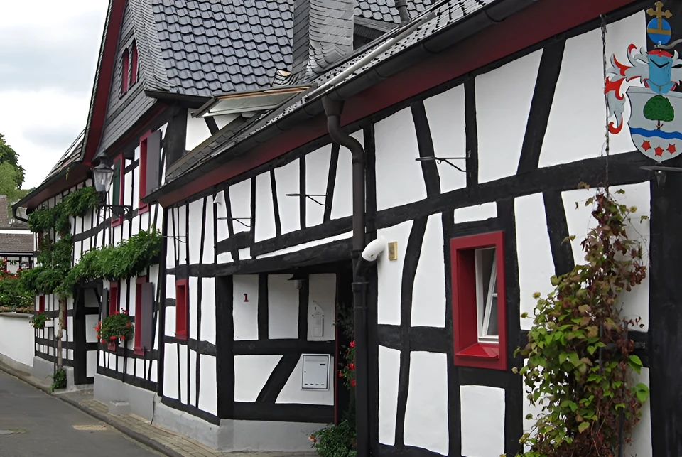 Straßenfassade eines umgebauten Fachwerkhauses mit roten Fensterrahmen in Bad Honnef